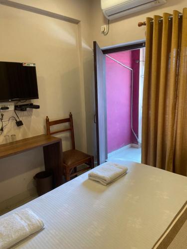 a bedroom with a bed and a window with a pink door at Plaza Tourist Home in Kannur