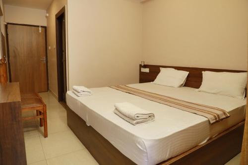 a bedroom with a bed with towels on it at Plaza Tourist Home in Kannur