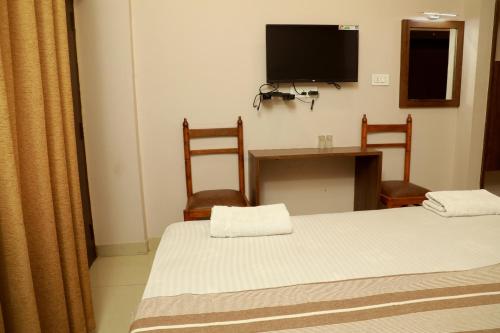 a room with two beds and a table and a television at Plaza Tourist Home in Kannur