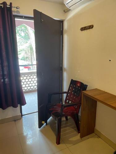 a chair in a room with a desk and a window at Plaza Tourist Home in Kannur