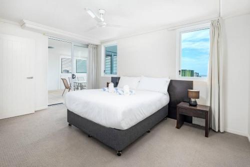 a bedroom with a large white bed and windows at Inner City Gem - Stunning Views in Cairns