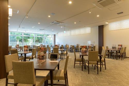 um restaurante com mesas e cadeiras em uma sala em ホテル京都エミナースManyonoyuHotelKyotoEminence em Quioto