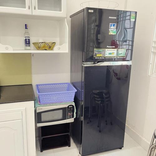 - un réfrigérateur noir dans la cuisine avec un tabouret dans l'établissement Mai Anh Garden 2, à Soc Trang