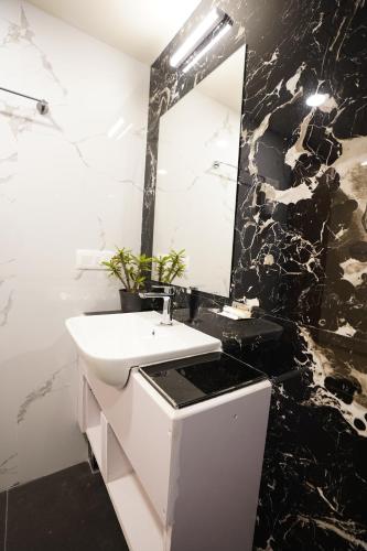 a black and white bathroom with a sink and a mirror at DrizzleDrop Inn Chennai in Chennai