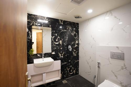 a bathroom with a sink and a black and white wall at DrizzleDrop Inn Chennai in Chennai
