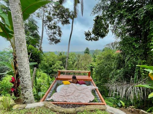 una persona acostada en una cama en un bosque en Kalamanthana Bali - Nature with Modern Comfort, en Selat