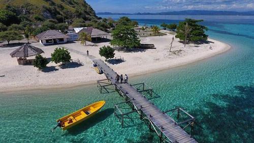 a boat on a dock in the water next to a beach at DAILY TRIP KOMODO TOUR in Labuan Bajo