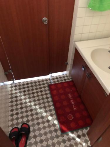 a bathroom with a sink and a red rug on the floor at Hanmadang in Osaka