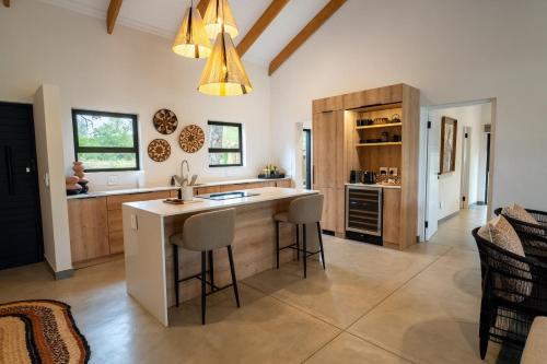 a kitchen with a island with bar stools at Nomads Den Safari Villas - Heated Pools and Riverbed views in Hoedspruit