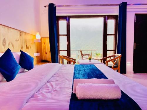 The Four Season Resort - Top Rated & Most Awarded Property in Mussoorie في موسوري: غرفة نوم بسرير كبير مع نافذة كبيرة