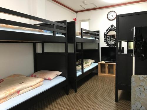 a room with two bunk beds and a clock at Hanmadang in Osaka