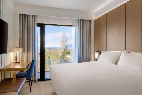 Habitación de hotel con cama, escritorio y ventana en AC Hotel by Marriott Saint-Julien-en-Genevois, en Saint-Julien-en-Genevois