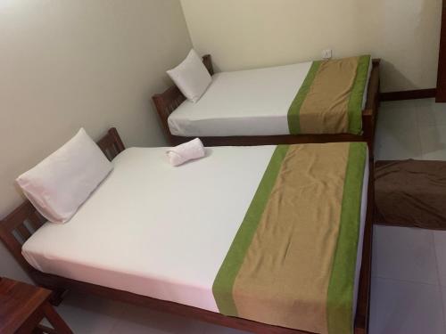 two twin beds in a small room at Cinnamon Tree Tourist Rest in Anuradhapura