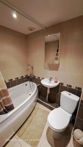 ein Badezimmer mit einer Badewanne, einem WC und einem Waschbecken in der Unterkunft Apartment Ramune in Šiauliai