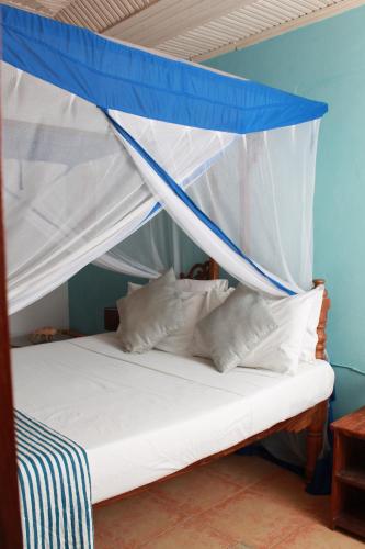 a bed with a blue and white canopy at Driftwood Beach Lodge in Jambiani