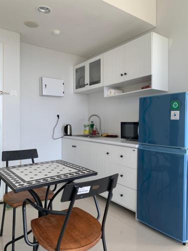 una cucina con tavolo e frigorifero blu di Two Bedroom Apartment at The Nove Nuvasa Bay Nongsa 306 a Nongsa