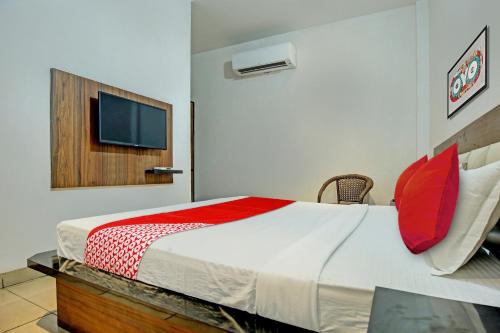 Schlafzimmer mit einem Bett mit roten Kissen und einem TV in der Unterkunft OYO Flagship 81231 Hotel Seven in Ludhiana