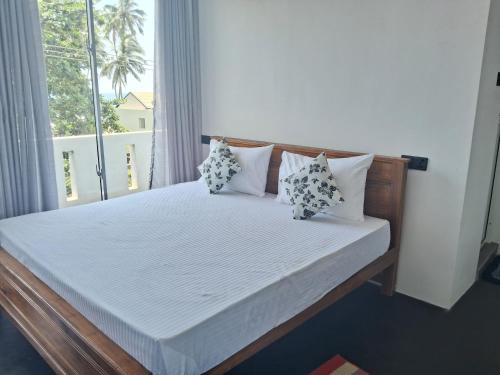 um quarto com uma cama com almofadas e uma janela em RKO Villa27 em Habaraduwa Central