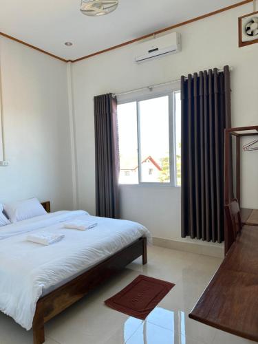 Un dormitorio con una cama grande y una ventana en narixay hotel, en Phonsavan