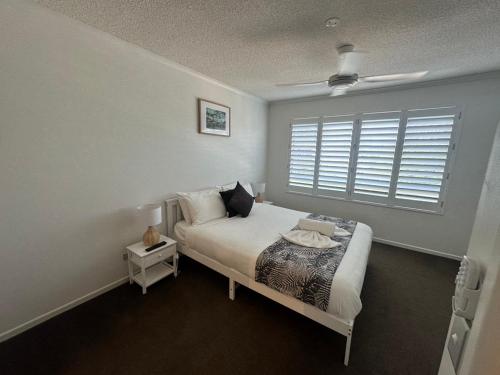 a white bedroom with a bed with a window at Kawana Waters Ocean Front Unit- Sunshine Coast in Buddina