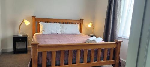 a bedroom with a wooden bed with two lamps at The Old Parsonage in Reefton