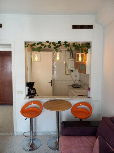 una cocina con mesa y 2 taburetes naranjas en Joli studio, 17 Avenue Hedi Nouira Ennasr 2, Ariana, Tunis, en Ariana