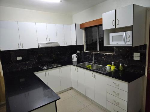 a kitchen with white cabinets and a black counter top at Bula Stay in Nadi