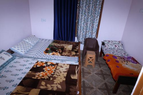 een slaapkamer met 2 aparte bedden en een gitaar bij HOTEL SHIVKRIPA AND RESTAURANT in Dharāsu