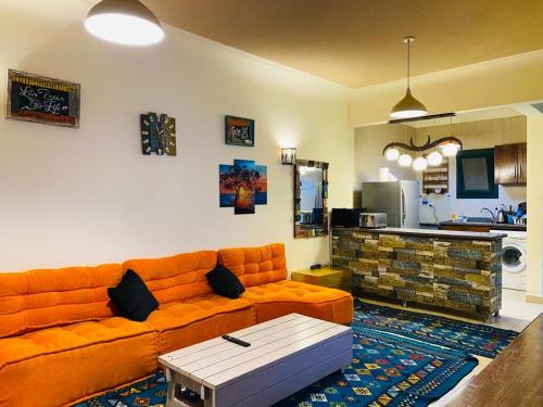 sala de estar con sofá naranja y cocina en Furnished Chalet Apartment at La Hacienda Ras Sedr en Ras Sedr