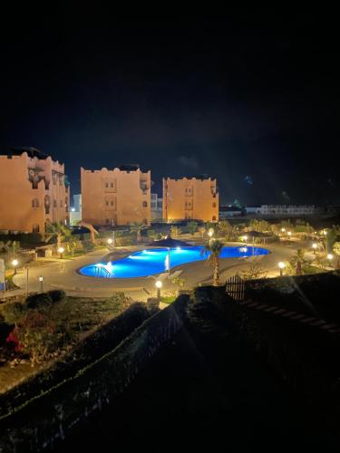 a large pool with blue lights in a city at night at Furnished Chalet Apartment at La Hacienda Ras Sedr in Ras Sedr