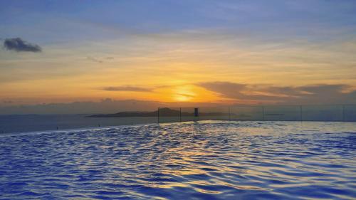 Copacabana Jomtien Luxury Residence & Yahaha في جومتين بيتش: مسبح لا نهاية له مع غروب الشمس في الخلفية