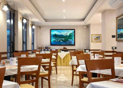 サン・ペッレグリーノ・テルメにあるHotel Avogadroのテーブルと椅子、大画面のレストランを併設しています。