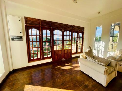 a living room with a couch and some windows at nuwaraelliya euphoria white house in Nuwara Eliya