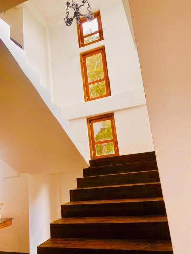 a staircase in a house with two windows at nuwaraelliya euphoria white house in Nuwara Eliya