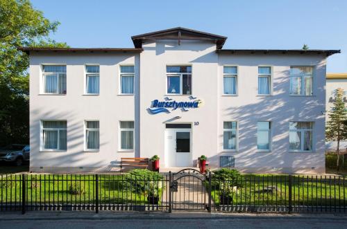 a white building with a gate in front of it at Bursztynowa Przy Morzu in Ustronie Morskie