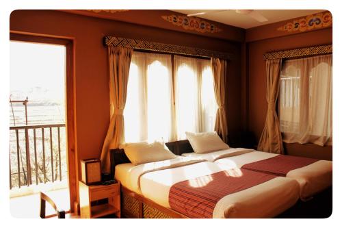 a bedroom with a bed and a balcony with windows at Hotel Jigmeling in Paro