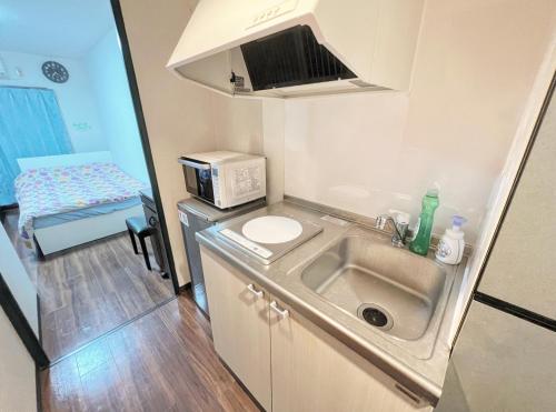 una pequeña cocina con fregadero y microondas en アルカイック401 en Tokio