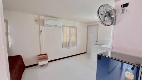 eine weiße Küche mit einem Ventilator an der Wand in der Unterkunft Aiem-Wilai Guesthouse in Surat Thani