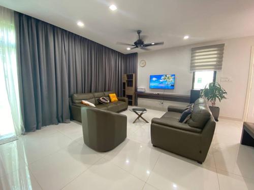 sala de estar con 2 sofás y TV de pantalla plana en MyHome Batu Feringghi Penang, en Batu Ferringhi