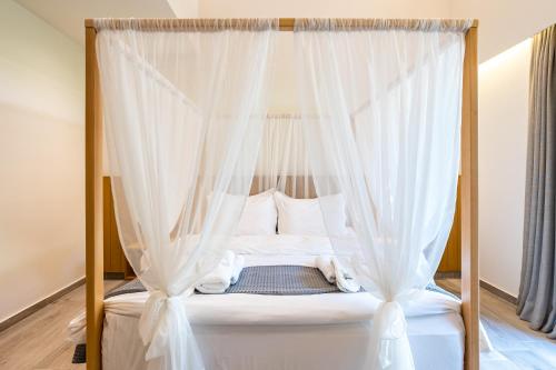 a bedroom with a canopy bed with white curtains at Denthis Hotel - Taygetos Mountain Getaway in Artemisía