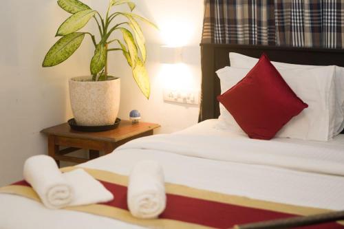 een slaapkamer met een bed met een rood kussen en een plant bij Kshetra Boutique Retreat Varkala in Varkala
