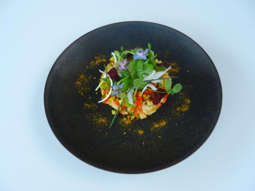 a black plate with a pizza and salad on it at La Maison Saint-Martin in Agonac