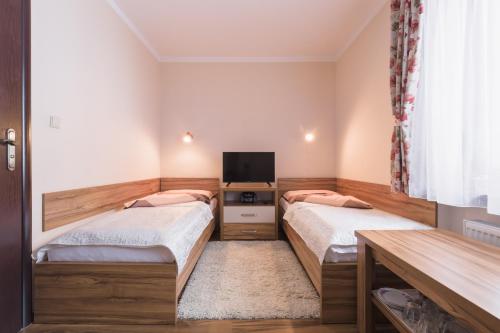 twee bedden in een kleine kamer met een tv bij Pokój u Zosi in Zakopane