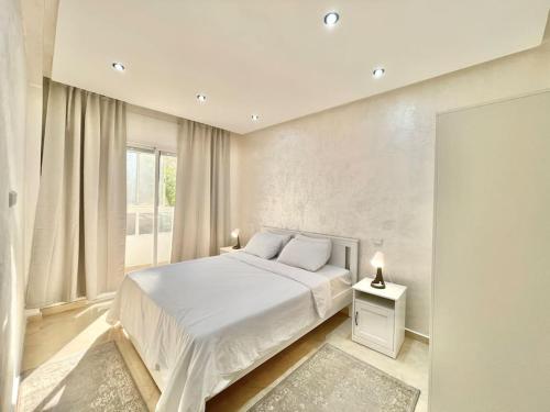 biała sypialnia z łóżkiem i oknem w obiekcie F4 Appartement entièrement neuf au cœur de Témara w mieście Temara
