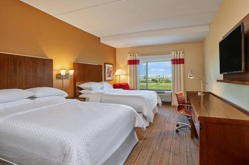a hotel room with three beds and a flat screen tv at Four Points by Sheraton Dallas Fort Worth Airport North in Coppell