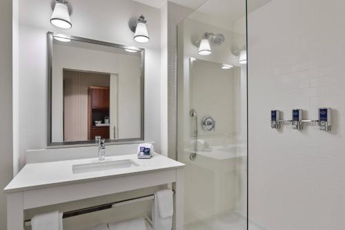 a white bathroom with a sink and a shower at Four Points by Sheraton Dallas Fort Worth Airport North in Coppell