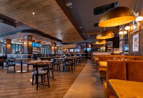 a restaurant with wooden floors and tables and chairs at Swissôtel Damian Jasna in Demanovska Dolina