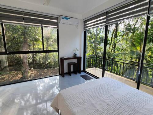 1 dormitorio con cama blanca y ventanas grandes en Eagle Nest, en Galle