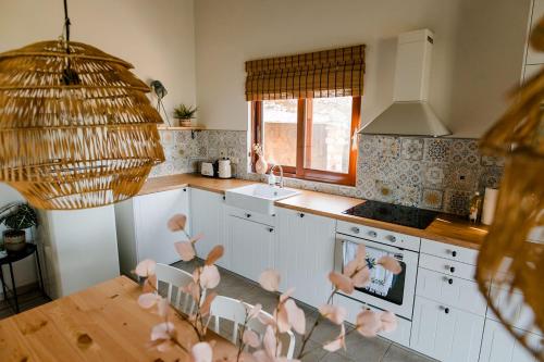 una cocina con armarios blancos y una mesa con flores rosas en Perivolakia Panorama House, en Perivolákia