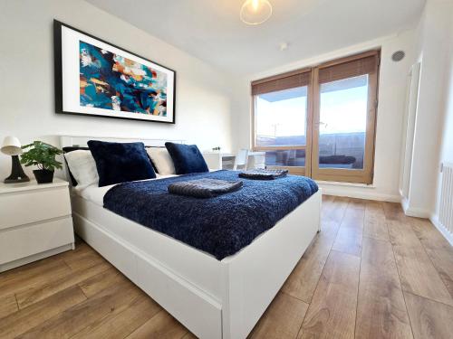 a bedroom with a large white bed with blue sheets at King’s Cross & Camden : Stylish Flat in London